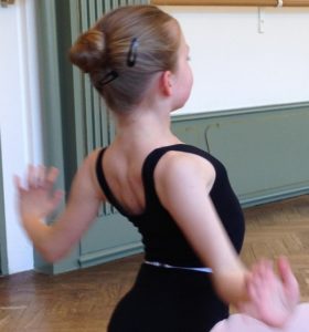 A child making a dance move with hervatms to the side, in a ballet class at Summerschool Den Haag.