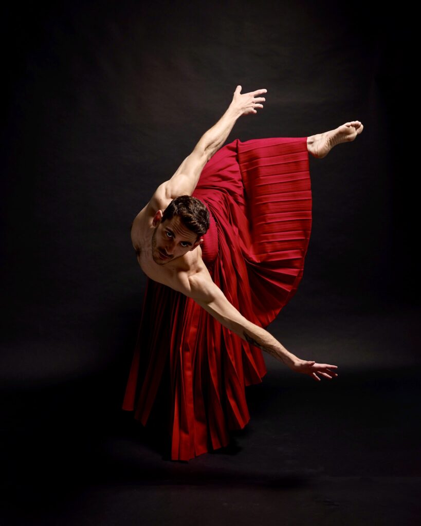 Alberto Tardanico performing in a flowing red skirt, captured mid-movement by Filibert Kraxner, showcasing his contemporary dance style and expression.