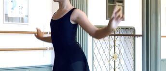 Ballet student wearing a skirt on demi-pointe reaching gracefully with arms during Youth Ballet at Summerschool Den Haag.